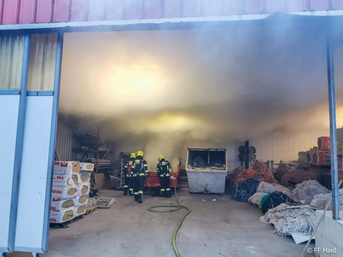 Abfallcontainer in einer Lagerhalle in Flammen